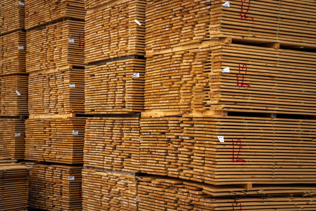 pexels photo 12278588 12278588 Close-up of neatly stacked wooden planks in an indoor warehouse setting.