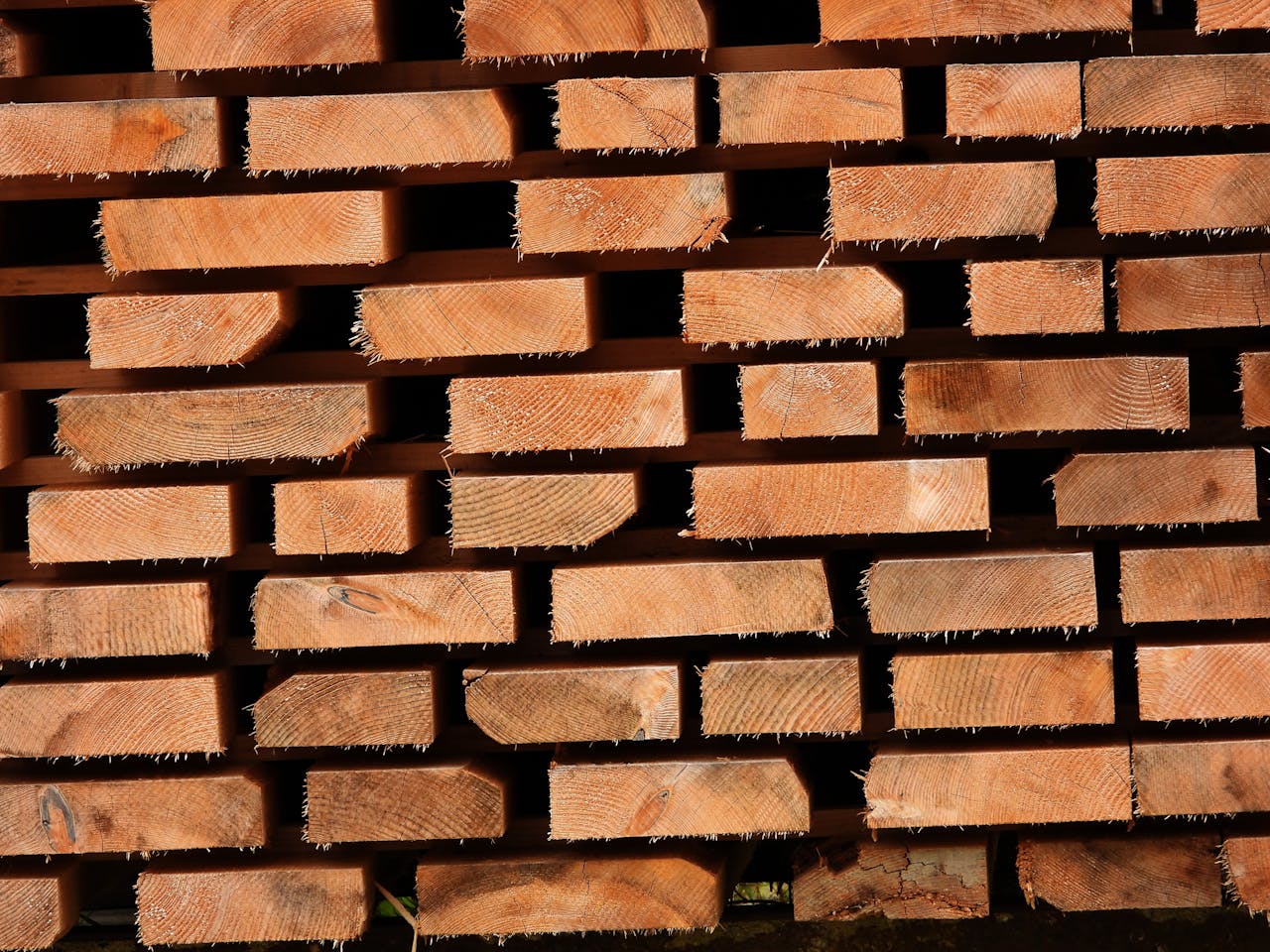 services-05 Close-up of stacked wooden planks showing texture and grain patterns.