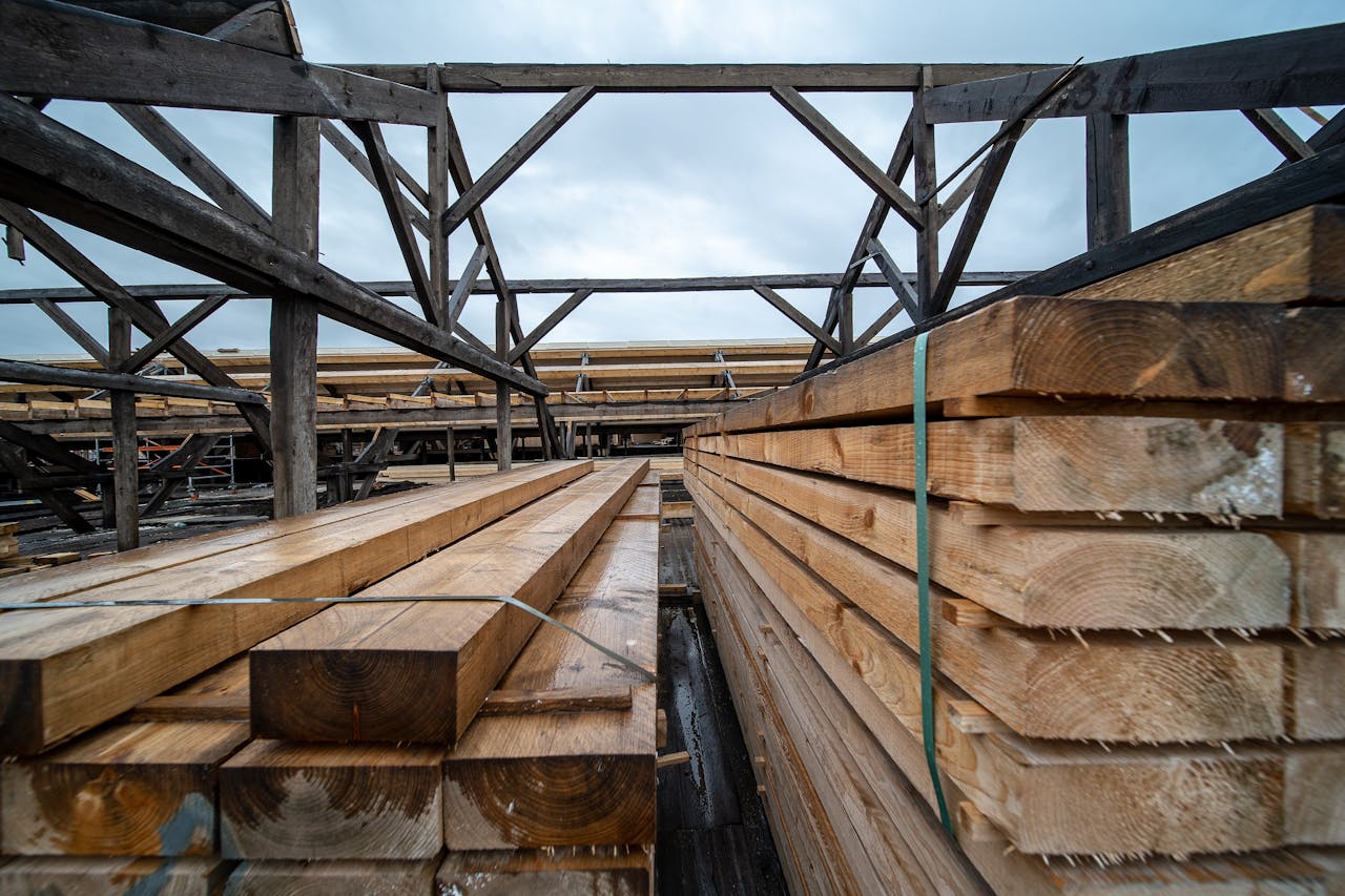 home-hero Stacked timber planks in an outdoor industrial storage area under a cloudy sky.